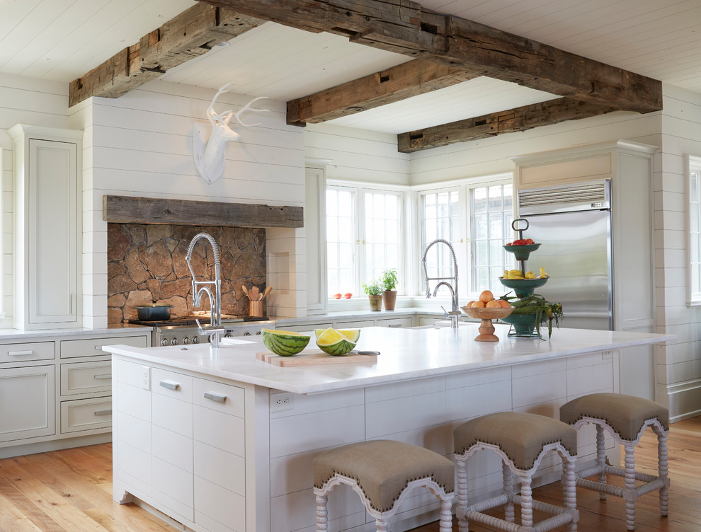 Inspiration for a beach style l-shaped kitchen in Birmingham with a farmhouse sink, beaded inset cabinets, white cabinets, stainless steel appliances, medium hardwood floors, with island and brown floor.