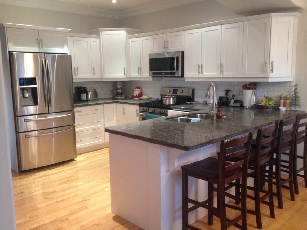 Eat-in kitchen - small transitional l-shaped light wood floor eat-in kitchen idea in Toronto with a double-bowl sink, shaker cabinets, white cabinets, quartz countertops, white backsplash, subway tile backsplash, stainless steel appliances and a peninsula