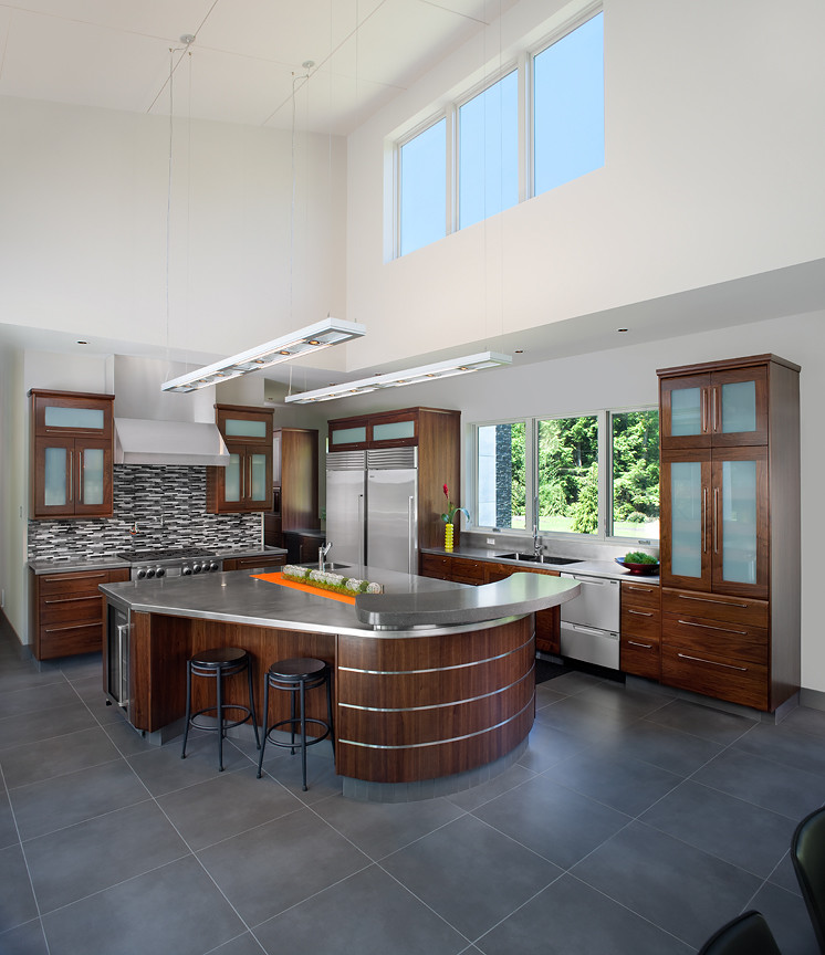 Photo of a large contemporary l-shaped open plan kitchen in Grand Rapids with a double-bowl sink, flat-panel cabinets, dark wood cabinets, stainless steel benchtops, white splashback, stainless steel appliances, with island and ceramic floors.