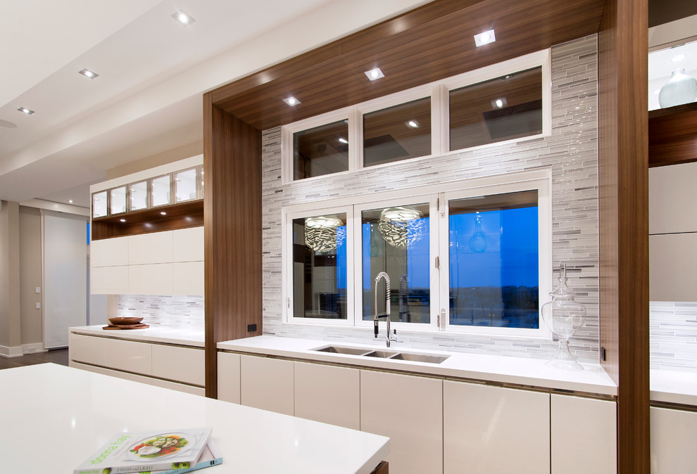 This is an example of a large contemporary l-shaped eat-in kitchen in Calgary with a triple-bowl sink, flat-panel cabinets, white cabinets, quartzite benchtops, multi-coloured splashback, matchstick tile splashback, stainless steel appliances, dark hardwood floors and with island.