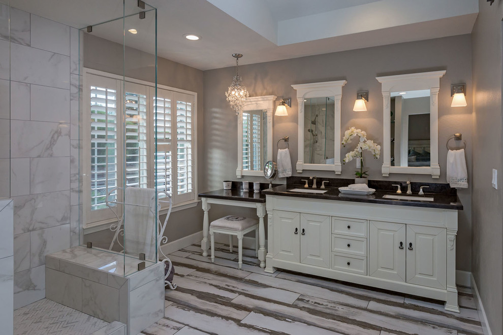 This is an example of a mid-sized traditional master bathroom in San Francisco with furniture-like cabinets, white cabinets, a corner shower, a two-piece toilet, marble, grey walls, porcelain floors, an undermount sink, engineered quartz benchtops, multi-coloured floor, a hinged shower door and black benchtops.