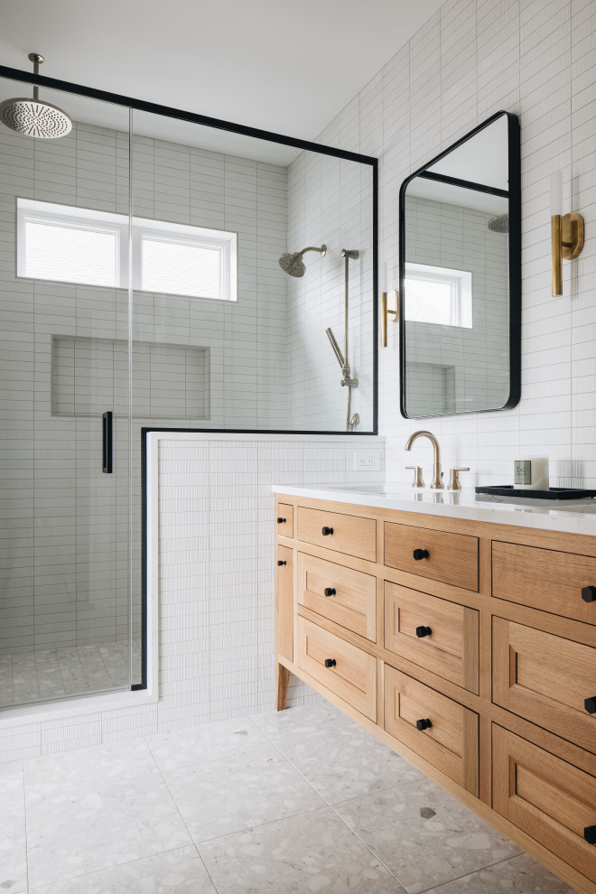 Photo of a nautical ensuite bathroom in Grand Rapids with light wood cabinets, all types of shower, white tiles, ceramic tiles, white walls, terrazzo flooring, a submerged sink, engineered stone worktops, a hinged door, white worktops and double sinks.