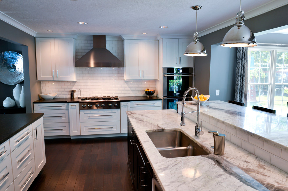 Transitional dark wood floor kitchen photo in Cleveland with a drop-in sink, recessed-panel cabinets, white backsplash, ceramic backsplash, stainless steel appliances and an island