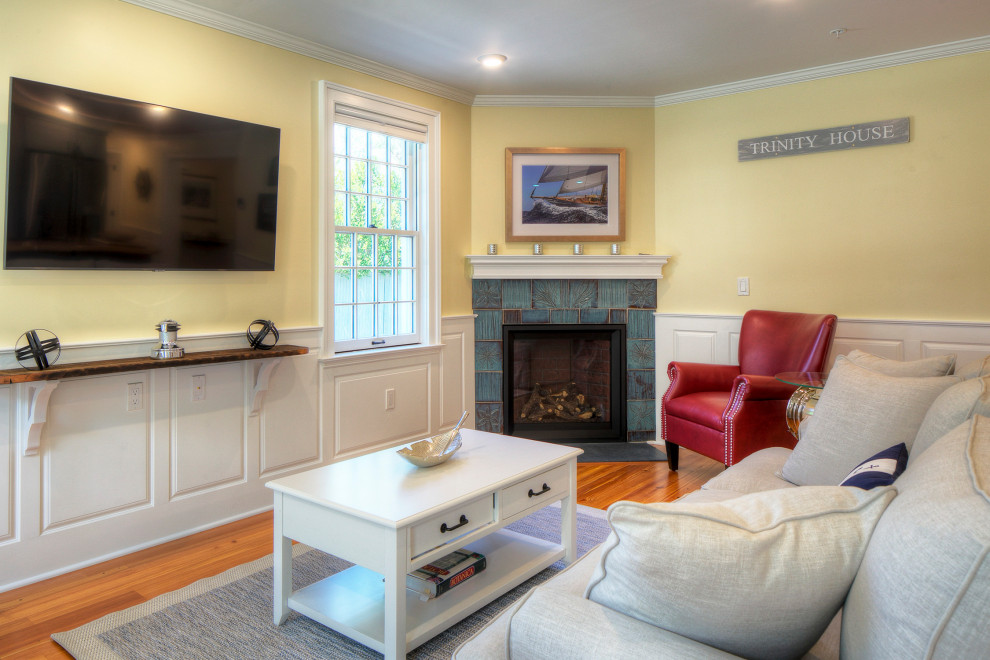 Offenes Klassisches Wohnzimmer mit gelber Wandfarbe, braunem Holzboden, Eckkamin, gefliester Kaminumrandung, TV-Wand, braunem Boden und vertäfelten Wänden in Providence