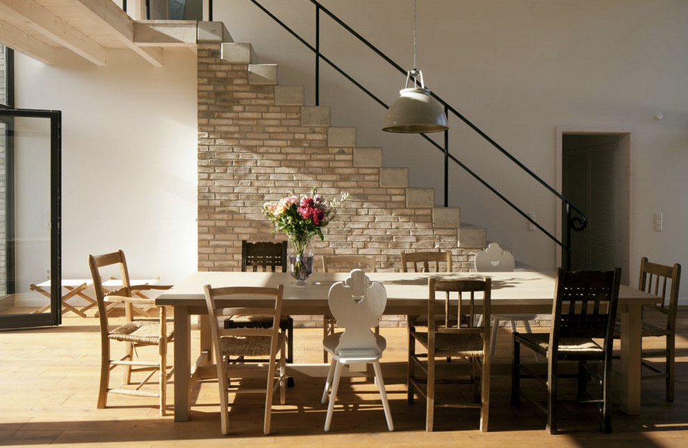 Photo of a large industrial dining room in Hamburg with white walls and light hardwood floors.