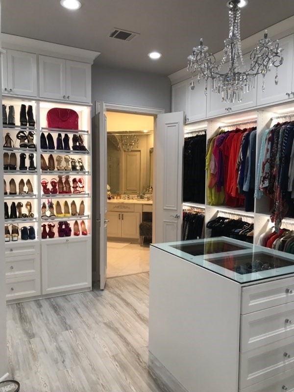 Design ideas for a large transitional gender-neutral walk-in wardrobe in Atlanta with glass-front cabinets, white cabinets and grey floor.