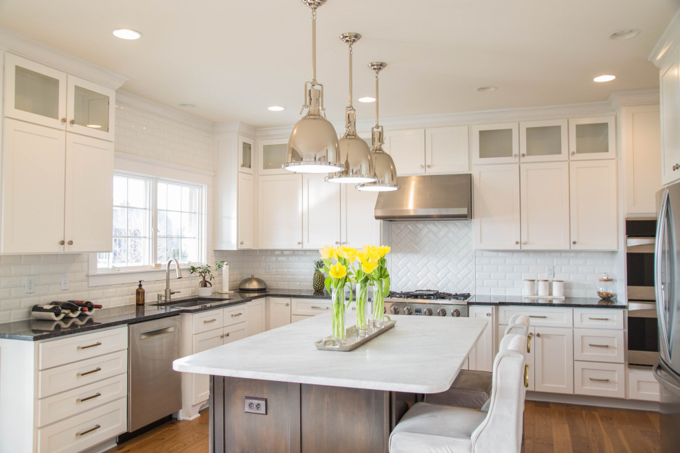 Inspiration for a large contemporary u-shaped medium tone wood floor and brown floor kitchen remodel in Indianapolis with an undermount sink, recessed-panel cabinets, white cabinets, marble countertops, white backsplash, subway tile backsplash, stainless steel appliances, an island and multicolored countertops