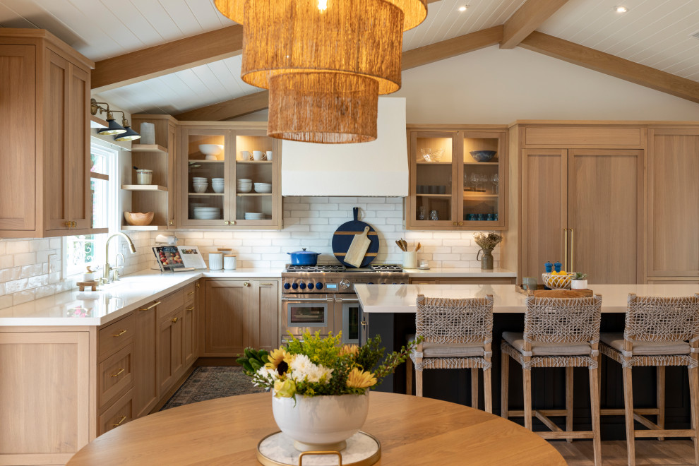 Photo of a beach style l-shaped kitchen in Los Angeles with shaker cabinets, light wood cabinets, white splashback, medium hardwood flooring, an island, brown floors, white worktops, exposed beams, a timber clad ceiling and a vaulted ceiling.
