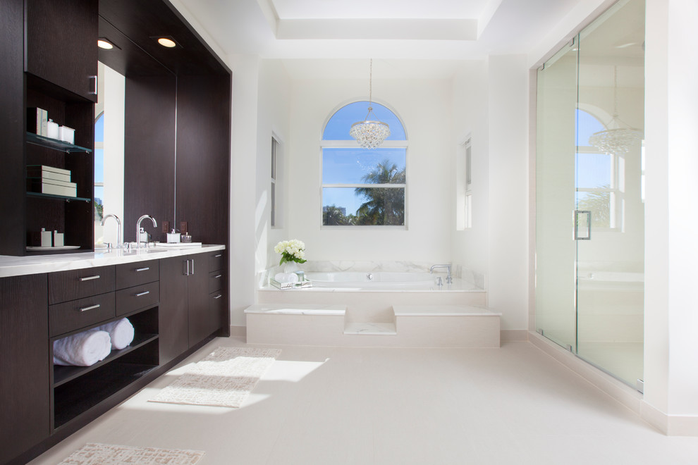 This is an example of a contemporary bathroom in Miami with flat-panel cabinets, dark wood cabinets, a drop-in tub, an alcove shower and white walls.