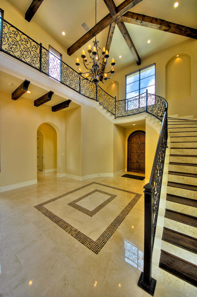 Design ideas for a large mediterranean foyer in Austin with yellow walls, marble floors, a single front door and a dark wood front door.