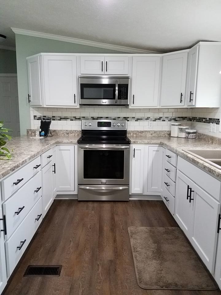 Photo of a small transitional u-shaped open plan kitchen in Chicago with white cabinets, stainless steel appliances, a peninsula and brown floor.