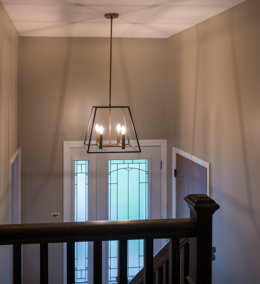 Inspiration for a small transitional u-shaped medium tone wood floor and brown floor single front door remodel in Chicago with an undermount sink, shaker cabinets, white cabinets, quartz countertops, white backsplash, ceramic backsplash, stainless steel appliances, an island, white countertops, beige walls and a white front door