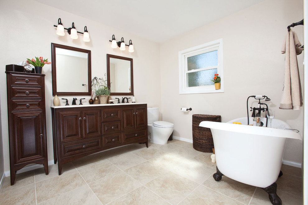 This is an example of a large traditional bathroom in Los Angeles with an undermount sink, recessed-panel cabinets, dark wood cabinets, a claw-foot tub, a two-piece toilet and beige walls.