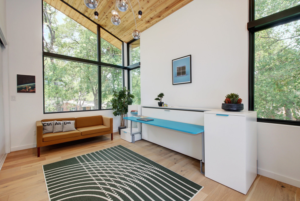 Großes Skandinavisches Arbeitszimmer mit Arbeitsplatz, weißer Wandfarbe, hellem Holzboden, freistehendem Schreibtisch, braunem Boden und gewölbter Decke in Austin