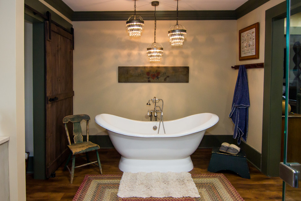 Example of a large mountain style master medium tone wood floor freestanding bathtub design with furniture-like cabinets, beige cabinets, a two-piece toilet, beige walls, an undermount sink, solid surface countertops and a hinged shower door