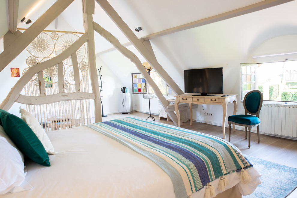 This is an example of a large traditional loft-style bedroom in Le Havre with white walls, medium hardwood floors and brown floor.