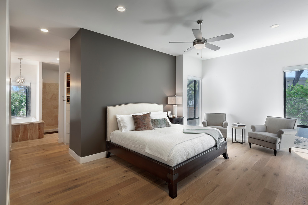 Photo of a mid-sized eclectic master bedroom in Austin with grey walls, medium hardwood floors, no fireplace and brown floor.