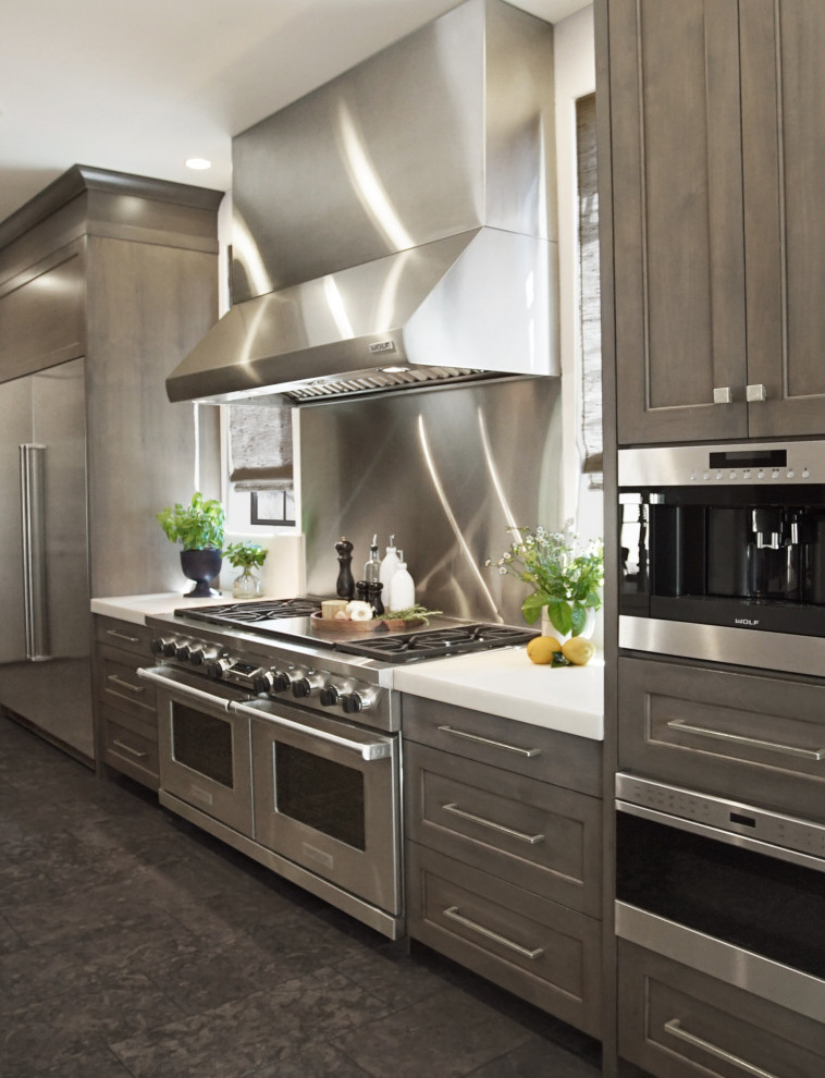 Inspiration for a large transitional u-shaped limestone floor and gray floor eat-in kitchen remodel with a farmhouse sink, shaker cabinets, brown cabinets, marble countertops, metallic backsplash, marble backsplash, stainless steel appliances, an island and white countertops