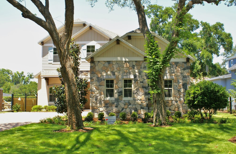 Mid-sized country two-storey beige house exterior in Orlando with stone veneer and a tile roof.