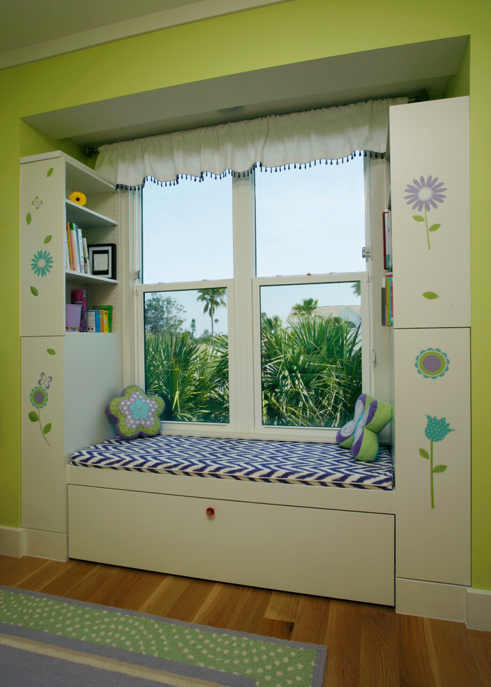 This is an example of a contemporary kids' bedroom for kids 4-10 years old and girls in Tampa with green walls and light hardwood floors.