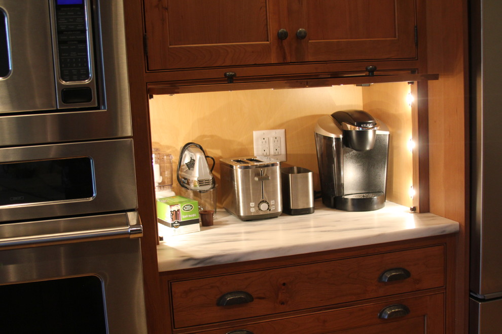 Eat-in kitchen - large transitional galley eat-in kitchen idea in Boston with raised-panel cabinets, marble countertops, stainless steel appliances, a farmhouse sink, medium tone wood cabinets and a peninsula