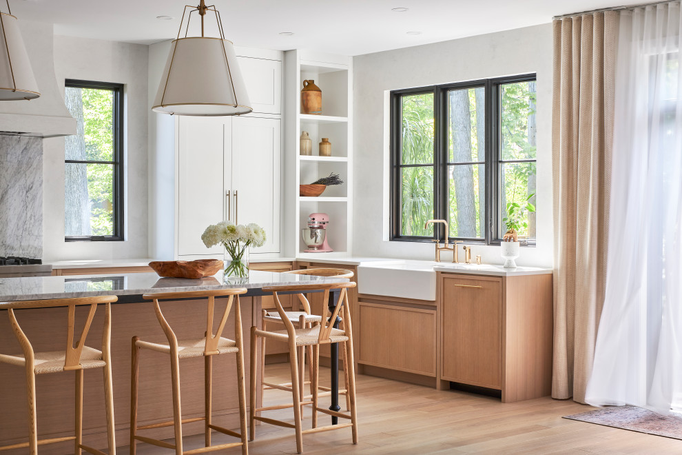 Inspiration for a transitional u-shaped light wood floor kitchen remodel in Ottawa with a farmhouse sink, shaker cabinets, white cabinets, marble countertops, multicolored backsplash, marble backsplash, paneled appliances, an island and multicolored countertops