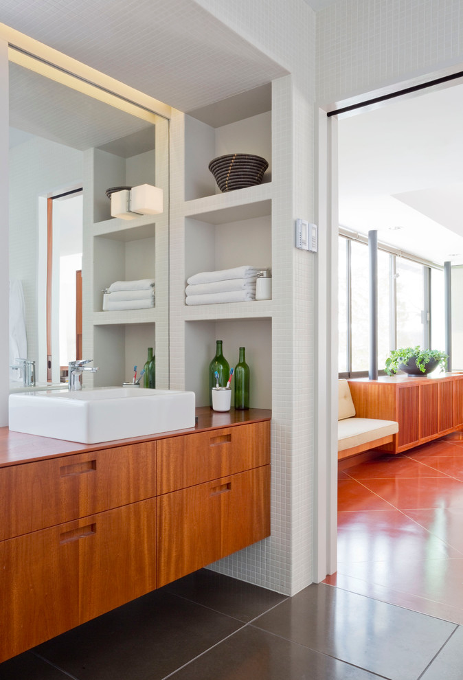 Photo of a mid-sized transitional master bathroom in New York with furniture-like cabinets, medium wood cabinets, a curbless shower, a one-piece toilet, white tile, ceramic tile, white walls, concrete floors, a vessel sink, wood benchtops, grey floor and an open shower.