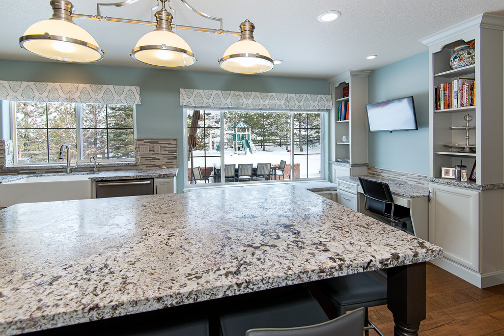 Large transitional medium tone wood floor enclosed kitchen photo with a farmhouse sink, recessed-panel cabinets, white cabinets, granite countertops, multicolored backsplash, matchstick tile backsplash, stainless steel appliances and an island