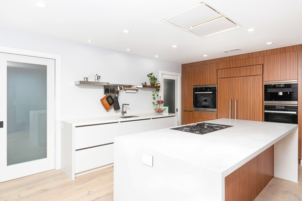 Design ideas for a mid-sized contemporary u-shaped eat-in kitchen in Los Angeles with a drop-in sink, flat-panel cabinets, white cabinets, quartz benchtops, stainless steel appliances, light hardwood floors, with island, beige floor and white benchtop.