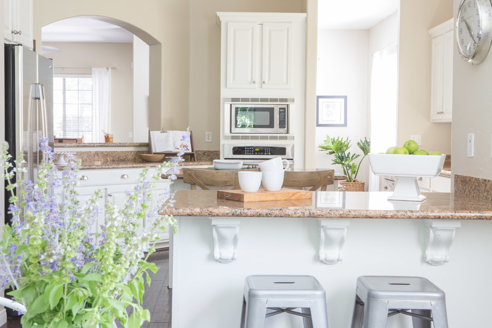 Inspiration for a mid-sized transitional u-shaped dark wood floor and brown floor eat-in kitchen remodel in Phoenix with a drop-in sink, raised-panel cabinets, white cabinets, granite countertops, brown backsplash, stainless steel appliances and two islands