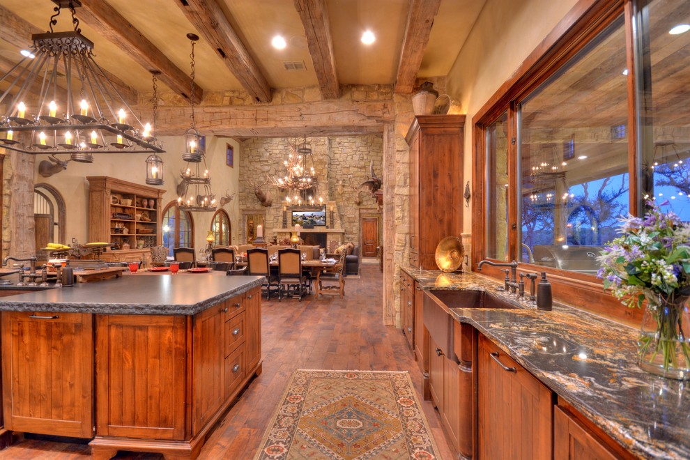 Example of a mountain style u-shaped medium tone wood floor eat-in kitchen design in Austin with a farmhouse sink, beaded inset cabinets, medium tone wood cabinets, granite countertops, stainless steel appliances and an island