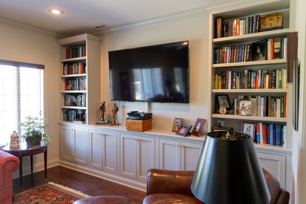 Foto de biblioteca en casa cerrada clásica de tamaño medio sin chimenea con paredes grises, suelo de madera oscura, televisor colgado en la pared y suelo marrón