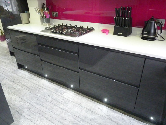 Gloss lacquered 'graphite' handleless kitchen with white quartz worktops contemporaneo-cocina