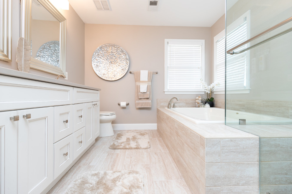 Photo of a transitional master bathroom in DC Metro with recessed-panel cabinets, white cabinets, a drop-in tub, a one-piece toilet, beige walls, beige floor and beige benchtops.