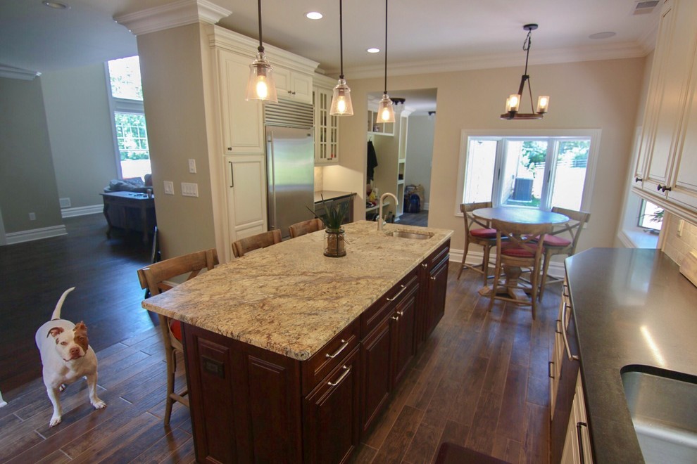 Photo of a mid-sized country l-shaped eat-in kitchen in New York with an undermount sink, raised-panel cabinets, white cabinets, quartzite benchtops, beige splashback, stainless steel appliances, dark hardwood floors, with island, brown floor and beige benchtop.