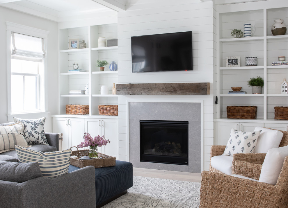 Inspiration for a large country enclosed family room in Chicago with white walls, light hardwood floors, a standard fireplace, a tile fireplace surround, a wall-mounted tv and beige floor.