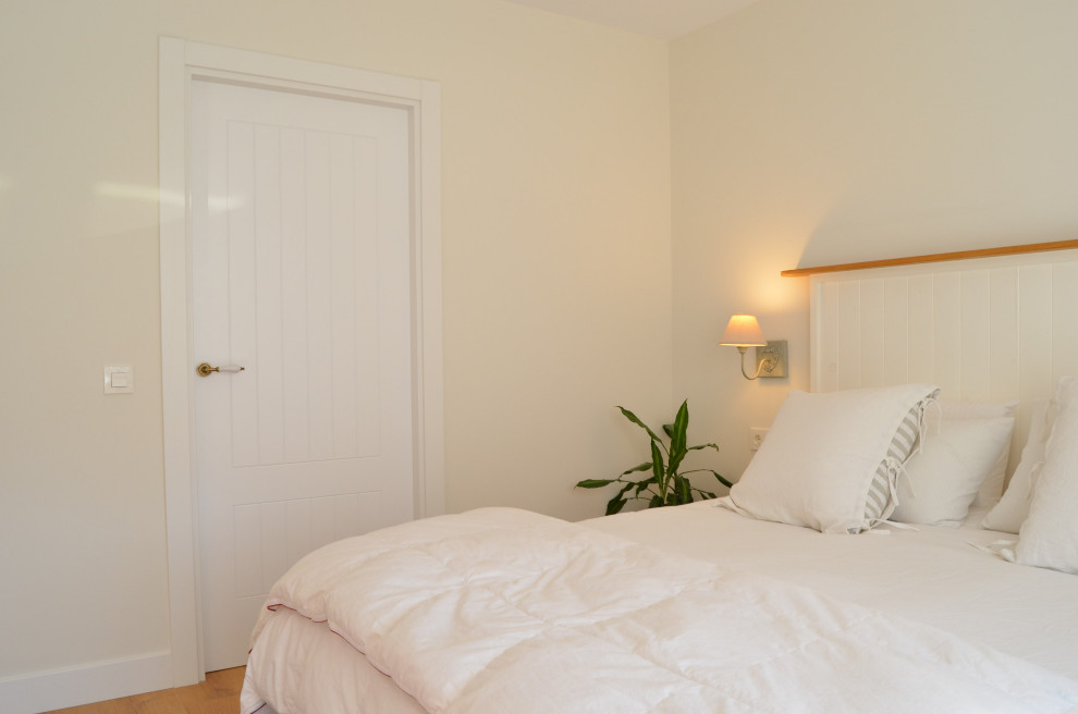 Ejemplo de dormitorio principal y beige y blanco nórdico de tamaño medio con suelo de madera en tonos medios, suelo marrón y papel pintado
