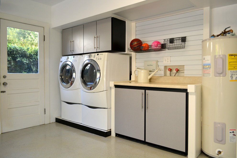 This is an example of a large contemporary single-wall utility room in Tampa with flat-panel cabinets, grey cabinets, laminate benchtops, white walls, concrete floors, a side-by-side washer and dryer and beige floor.