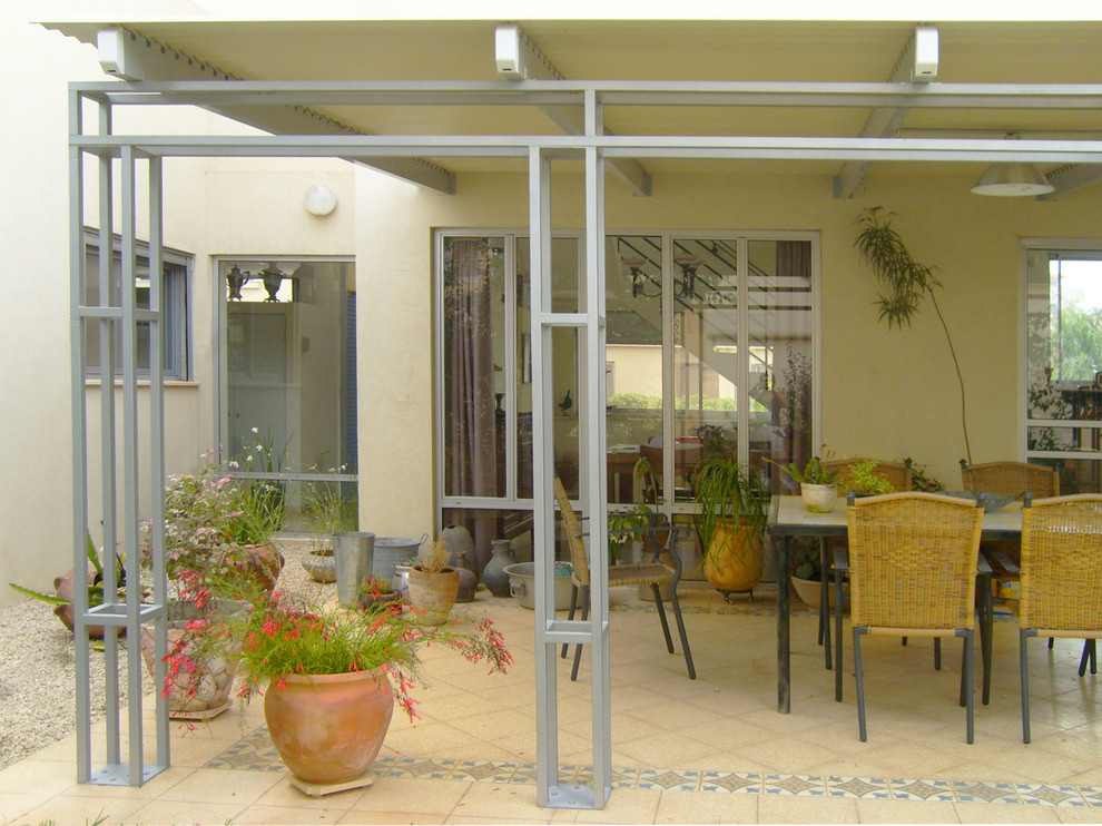 Mid-sized mediterranean courtyard patio in Other with a container garden, gravel and an awning.
