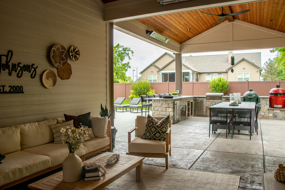 Esempio di un patio o portico di medie dimensioni e dietro casa con un caminetto, cemento stampato e un tetto a sbalzo