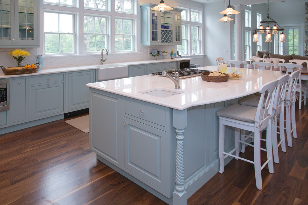 Inspiration for a large beach style l-shaped eat-in kitchen in Boston with white splashback, mosaic tile splashback, a farmhouse sink, beaded inset cabinets, blue cabinets, marble benchtops, stainless steel appliances, dark hardwood floors and with island.