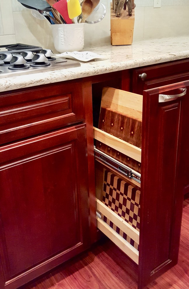 Example of a large transitional u-shaped medium tone wood floor eat-in kitchen design with raised-panel cabinets, medium tone wood cabinets, granite countertops, beige backsplash, ceramic backsplash, stainless steel appliances and an island
