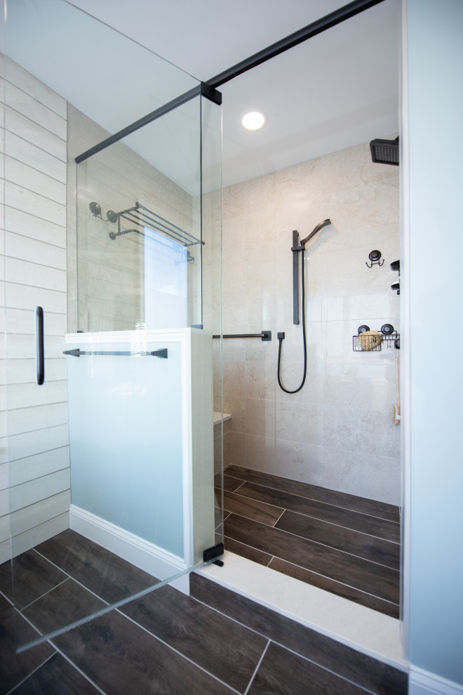 Mid-sized beach style master beige tile and porcelain tile porcelain tile, brown floor, single-sink and shiplap wall bathroom photo in Philadelphia with shaker cabinets, white cabinets, white walls, a vessel sink, granite countertops, a hinged shower door, multicolored countertops and a built-in vanity
