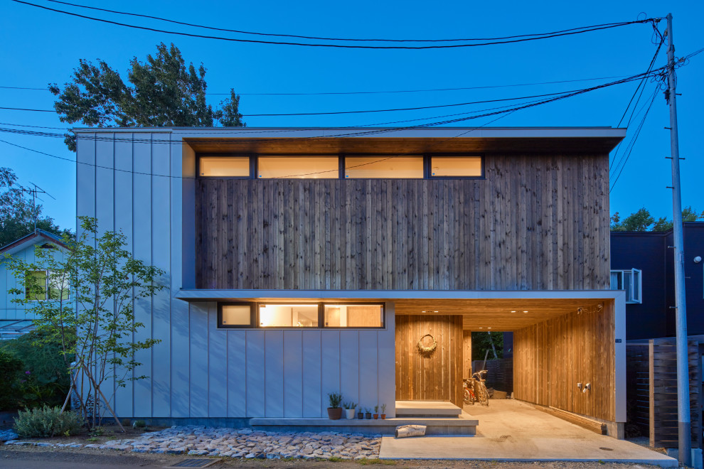 Inspiration for an industrial two-storey multi-coloured house exterior in Sapporo with mixed siding and a flat roof.
