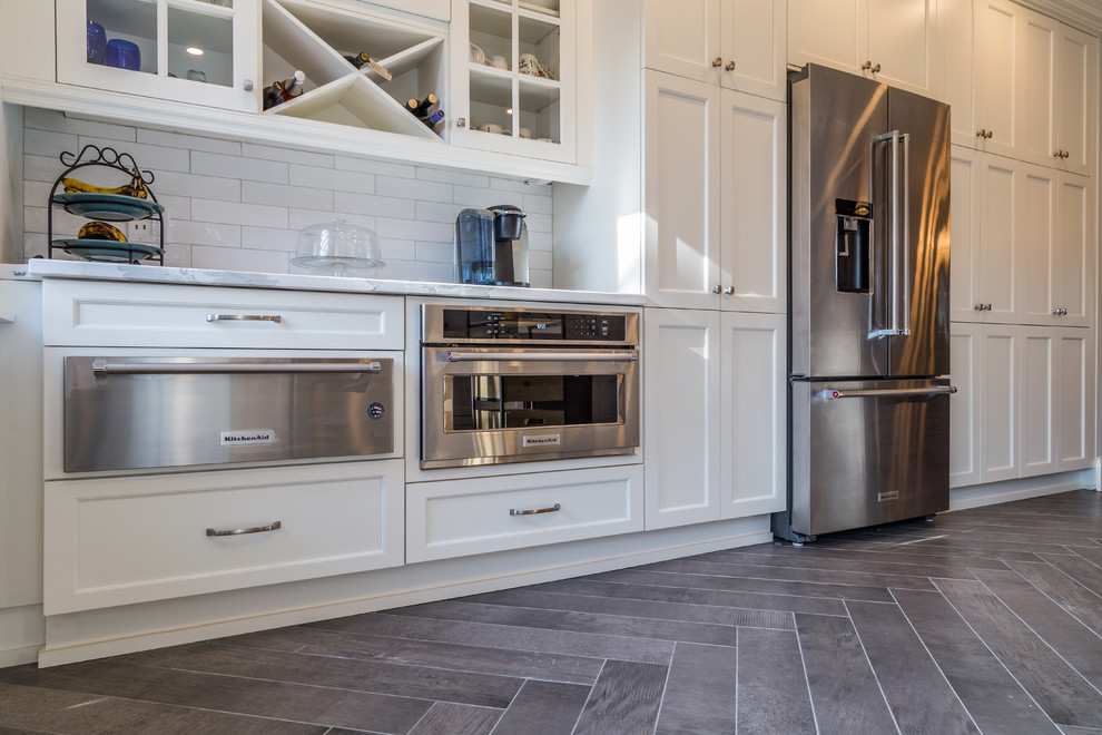 Example of a mid-sized transitional u-shaped ceramic tile kitchen pantry design in Toronto with a double-bowl sink, shaker cabinets, white cabinets, white backsplash, subway tile backsplash, stainless steel appliances and a peninsula