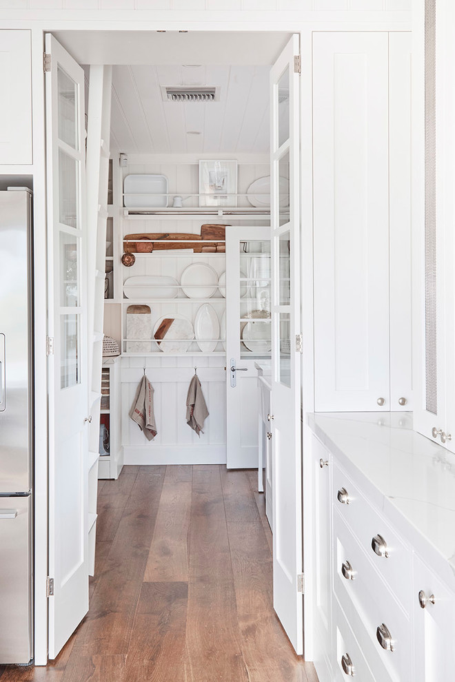 Photo of a mid-sized country u-shaped kitchen pantry in Sydney with a farmhouse sink, shaker cabinets, white cabinets, marble benchtops, white splashback, subway tile splashback, stainless steel appliances, light hardwood floors and with island.