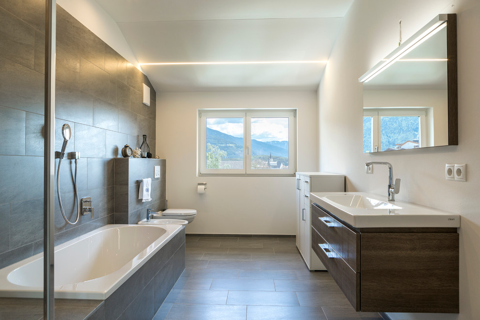 Large contemporary master bathroom in Other with flat-panel cabinets, dark wood cabinets, a drop-in tub, a shower/bathtub combo, a bidet, brown tile, ceramic tile, white walls, porcelain floors and an integrated sink.