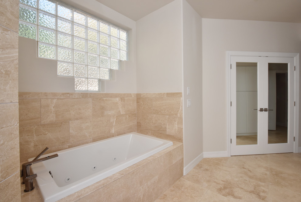 Large contemporary master bathroom in Phoenix with flat-panel cabinets, white cabinets, a drop-in tub, an alcove shower, beige tile, travertine, beige walls, travertine floors, an undermount sink, solid surface benchtops, beige floor and a hinged shower door.