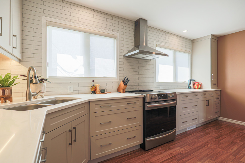 Inspiration for a mid-sized transitional l-shaped vinyl floor and brown floor eat-in kitchen remodel in Edmonton with an undermount sink, shaker cabinets, beige cabinets, quartz countertops, white backsplash, ceramic backsplash, stainless steel appliances, no island and white countertops