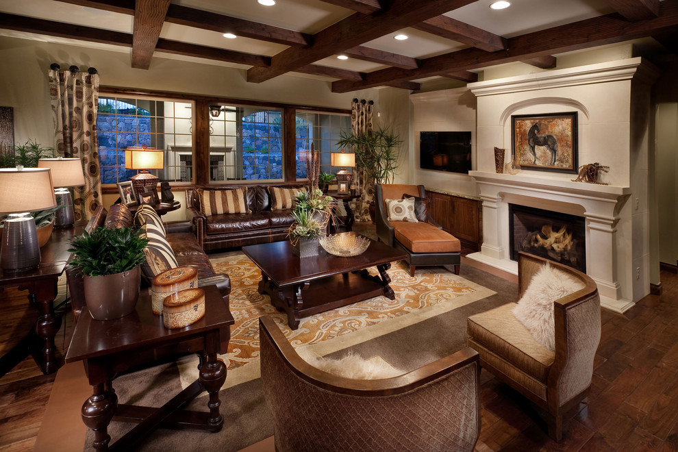 Photo of a mediterranean open concept family room in Denver with beige walls, dark hardwood floors, a standard fireplace and a wall-mounted tv.